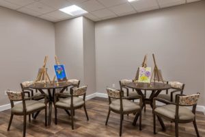 An art room with easels and paintings set up on tables.