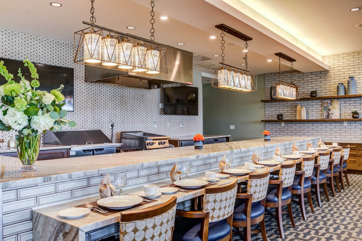A modern restaurant interior featuring bar seating, elegant lighting, and a sleek countertop.