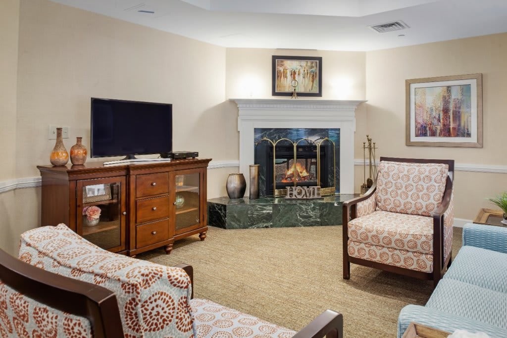 A cozy living room with a fireplace and television, featuring comfortable seating and tasteful decor.