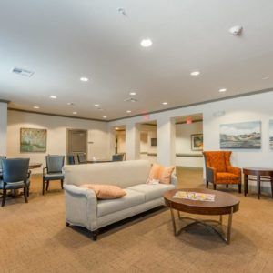 A modern lounge area featuring a comfortable sofa, armchair, and coffee table surrounded by artwork and ambient lighting.