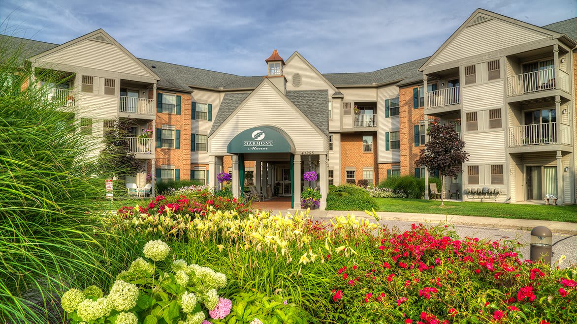 A beautifully landscaped entrance to an apartment building with a variety of colorful flowers.