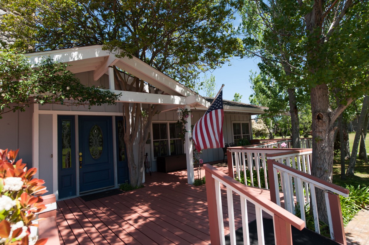 A quaint house with a blue door and an American flag on a sunny day.