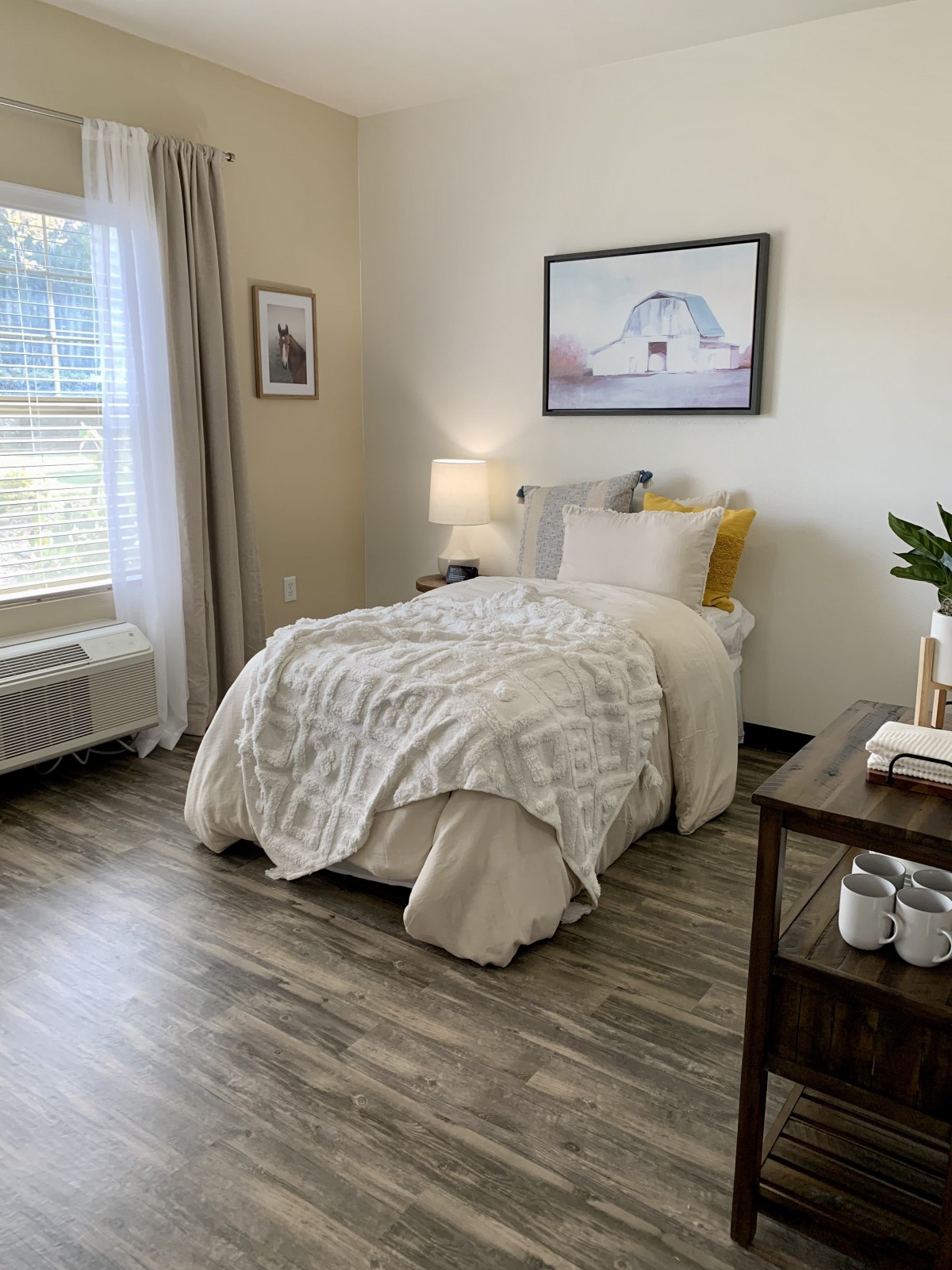 A cozy and modern bedroom featuring a single bed with soft bedding, a bedside table with a lamp, and wall art.