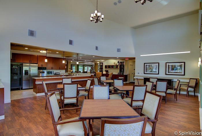A spacious and elegantly designed dining area with wooden tables and upholstered chairs.