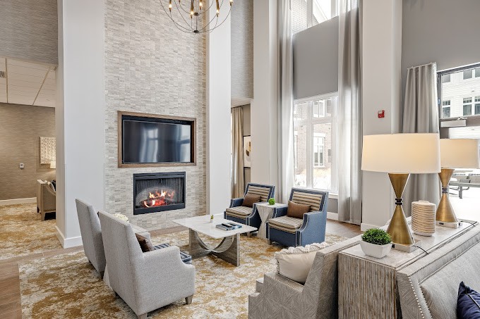 A modern living room with a fireplace and comfortable seating area, featuring high ceilings and ample natural light.