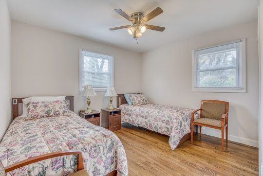 A cozy bedroom featuring two beds with floral bedding and a ceiling fan.