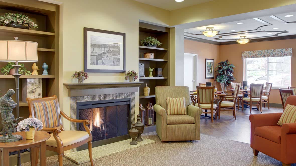 A cozy living room with a fireplace, armchair, and decorative shelves.