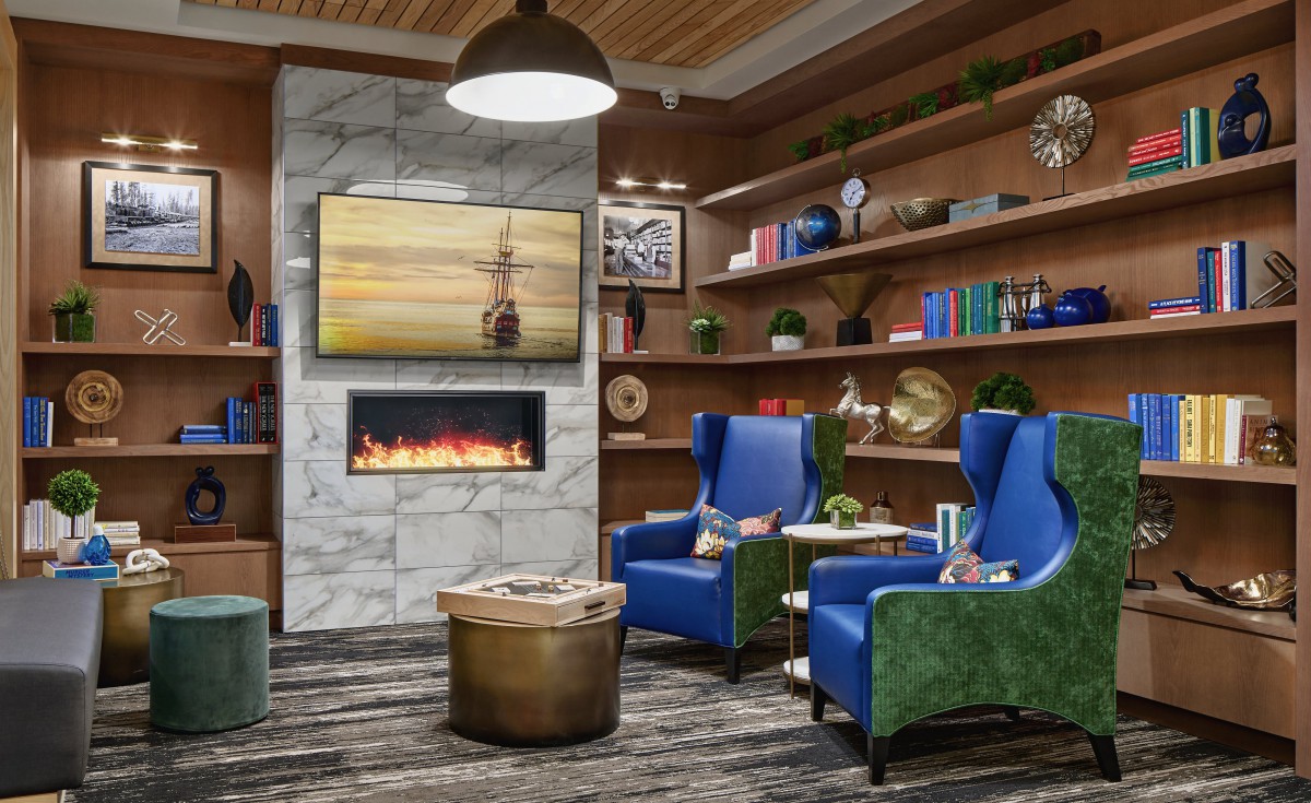 A cozy living room with modern design elements, featuring a fireplace, blue armchairs, and bookshelves.
