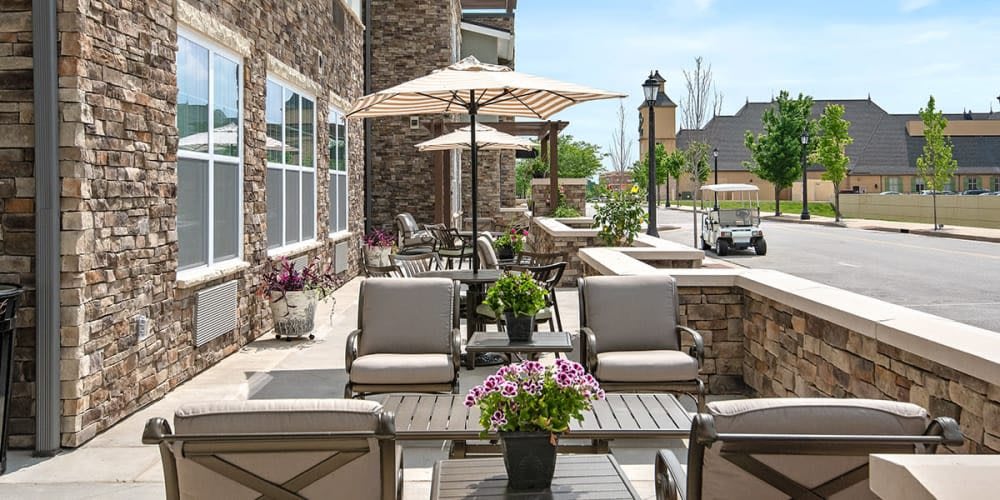 A charming outdoor patio with comfortable seating, umbrellas, and vibrant flowers.