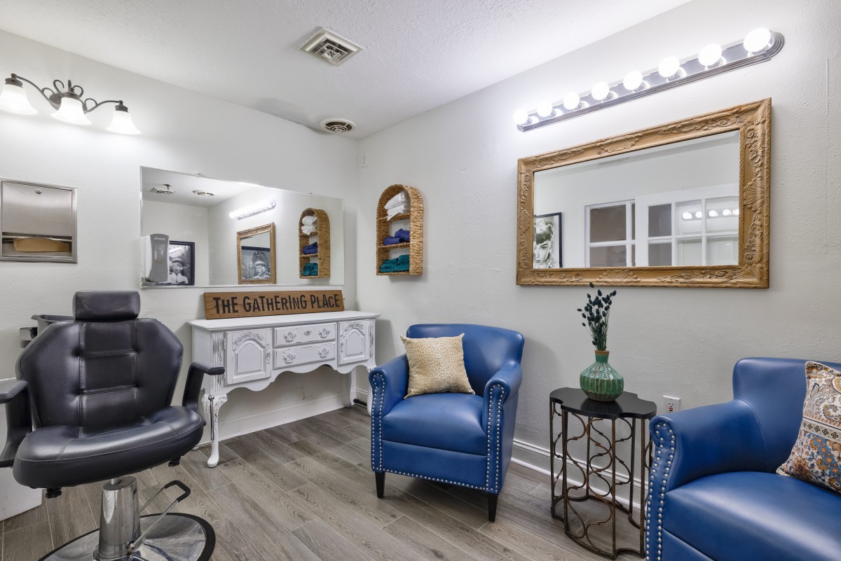 A stylishly decorated salon interior featuring blue chairs, a large mirror, and elegant lighting.