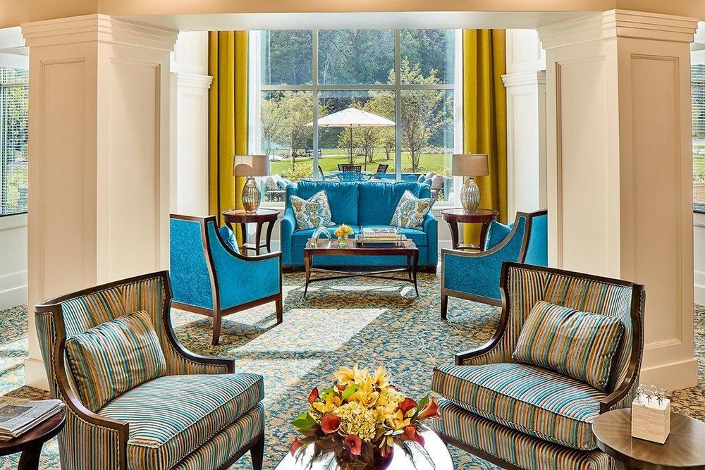 A modern living room with blue chairs and large windows, featuring elegant decor and bright colors.