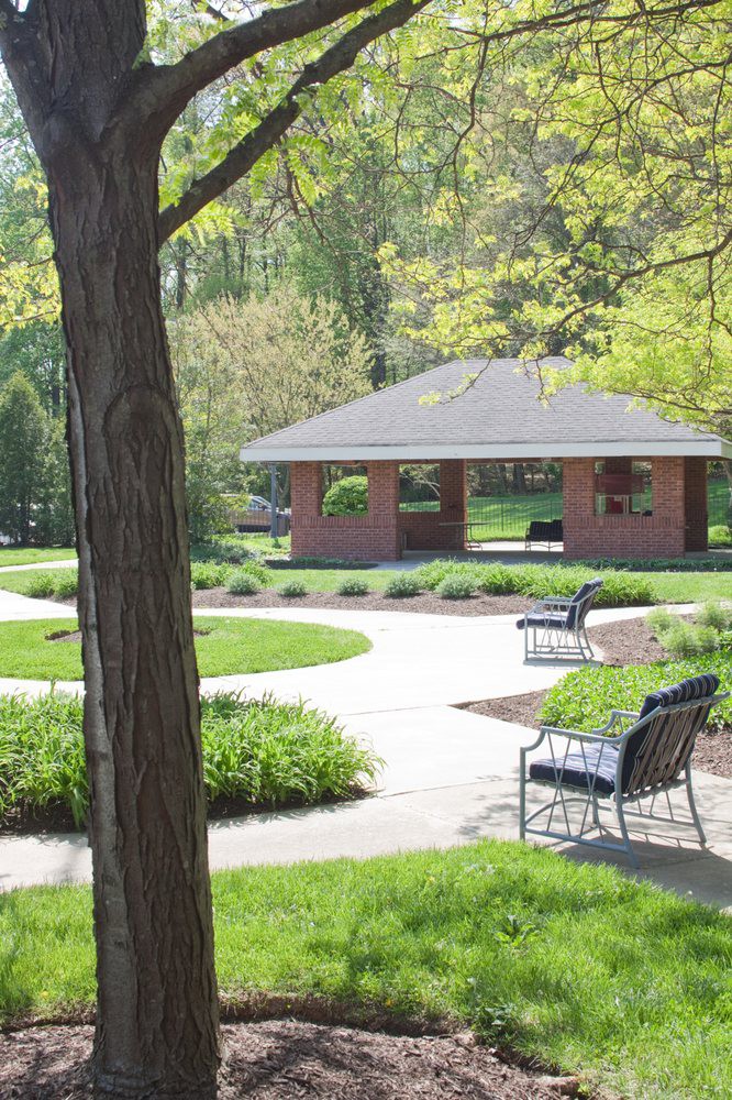 A peaceful park with benches, a gazebo, and a winding pathway surrounded by lush greenery.