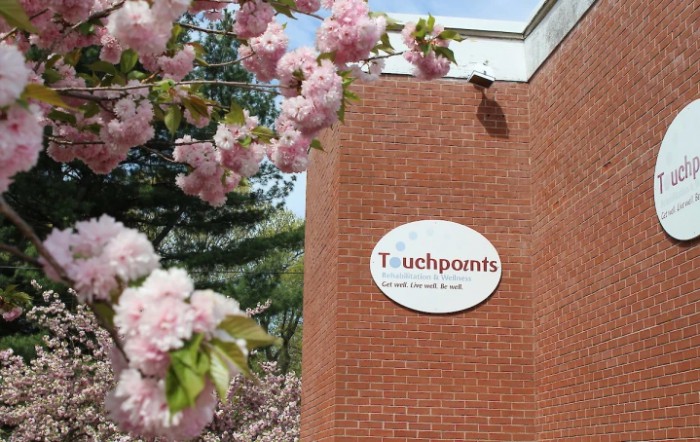 A brick building with a 'Touchpoints' sign, surrounded by blooming pink flowers.