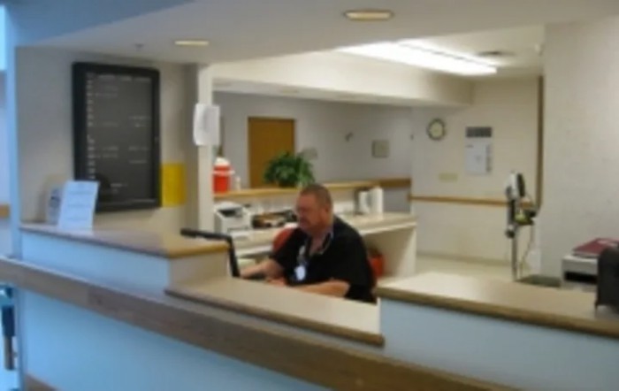 A person working at a reception desk with a computer in an office setting.