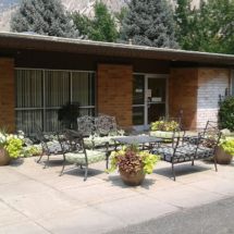 An inviting patio area with metal furniture and potted plants outside a building.