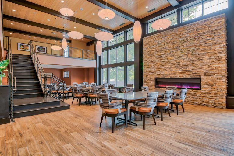 Modern restaurant interior with large windows, stylish furniture, and a cozy fireplace.