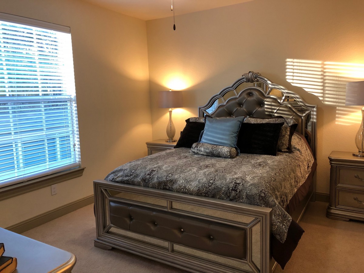 A cozy bedroom with a neatly made bed and ambient lighting.