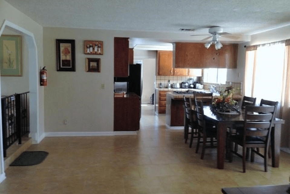 An open-plan kitchen and dining area with wooden cabinets and a dining table.