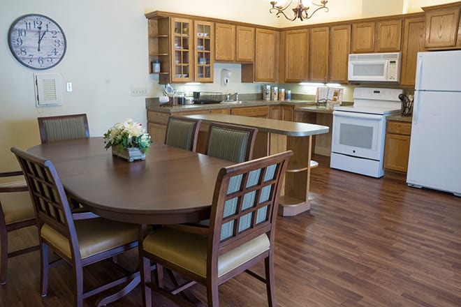 A cozy kitchen with wooden cabinets and a dining area featuring a round table with chairs.