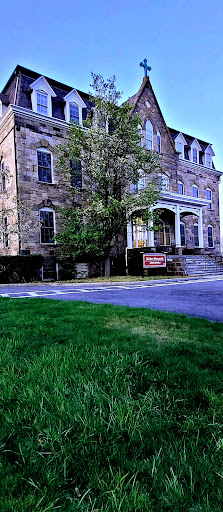 A historic stone building featuring a grand entrance and well-maintained front yard.