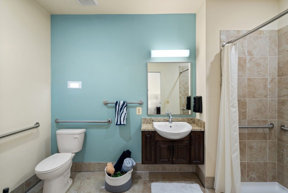 A modern bathroom featuring a sink, toilet, shower, and towels neatly arranged.