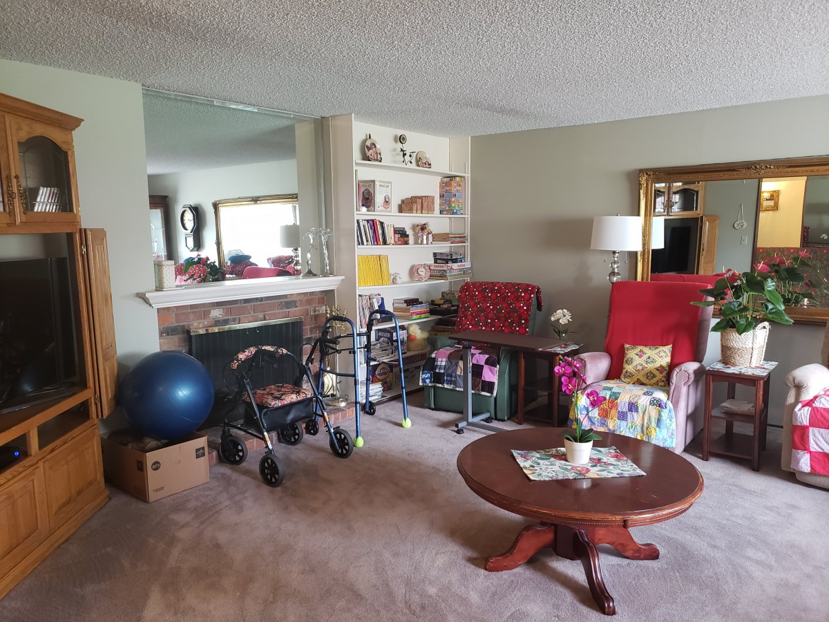 A cozy living room featuring red chairs, a wooden coffee table, and shelving filled with books and decor.