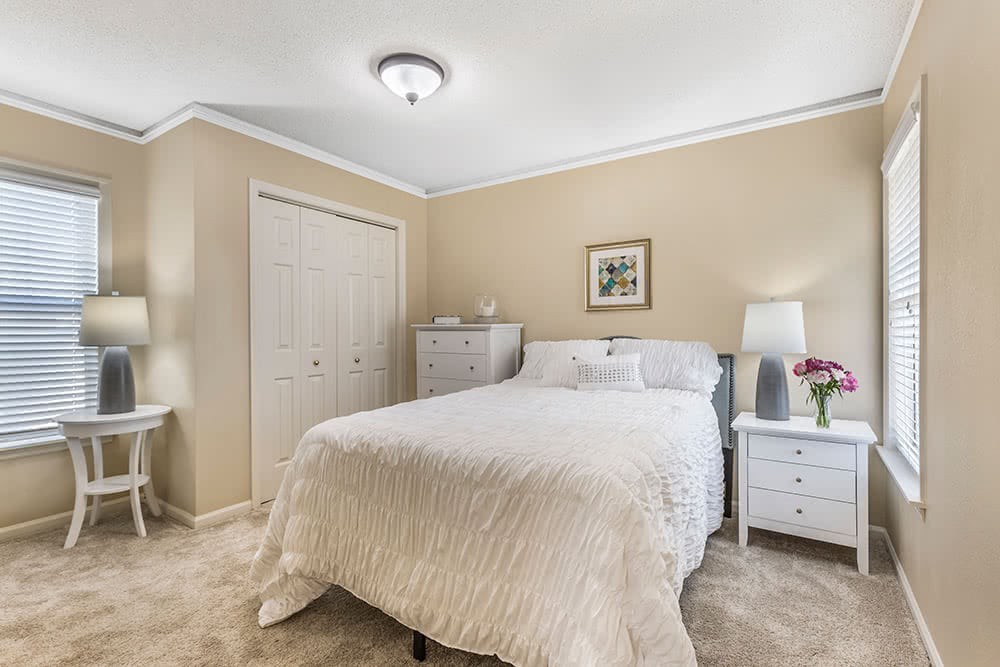 A cozy bedroom with neutral colors and simple decor, featuring a bed, nightstands, and lamps.