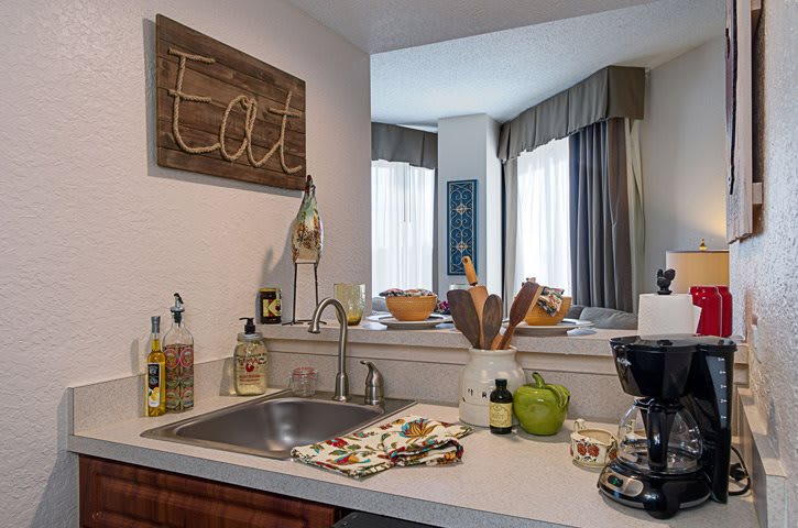 A cozy kitchen area with a sink and countertop, adorned with various decor items and appliances.