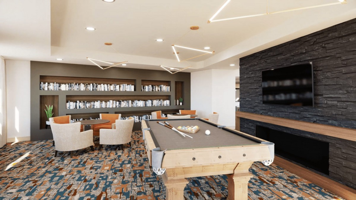 A modern lounge area featuring a billiards table and library with comfortable seating.