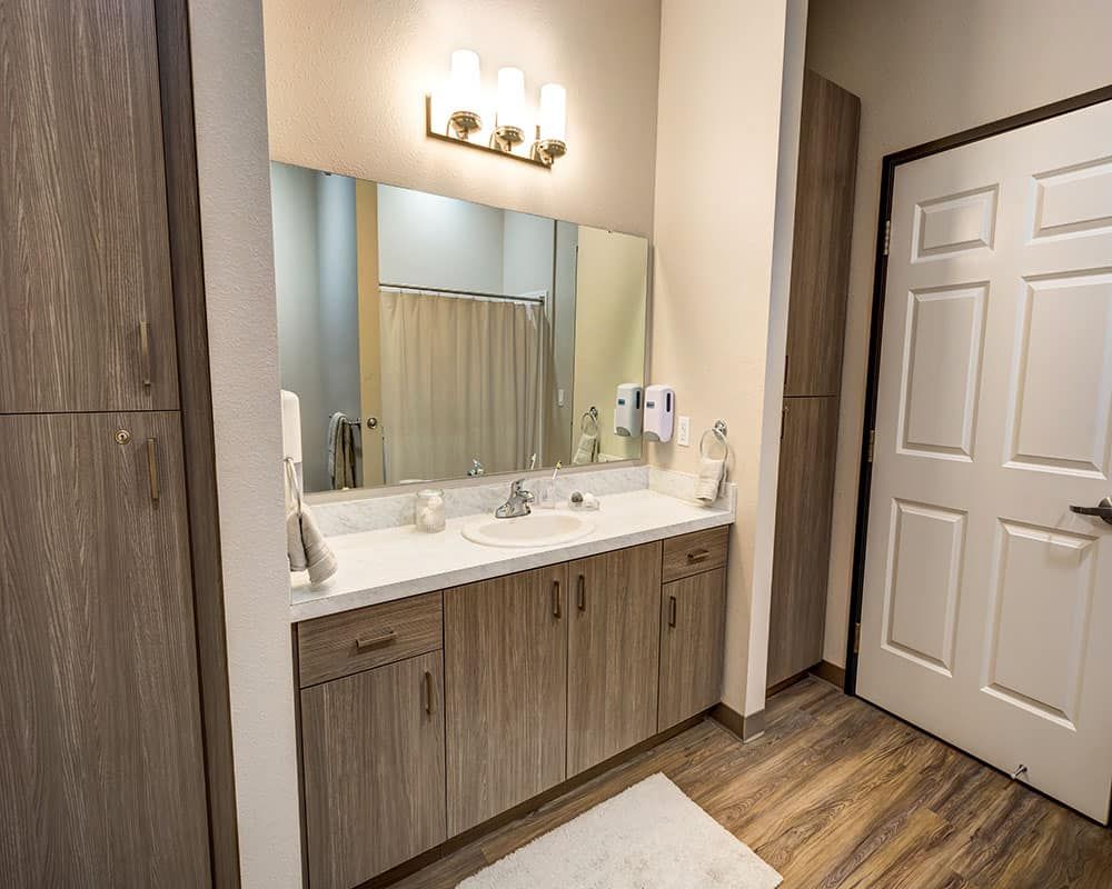 A modern bathroom with a large mirror and a wooden vanity featuring dual sinks.