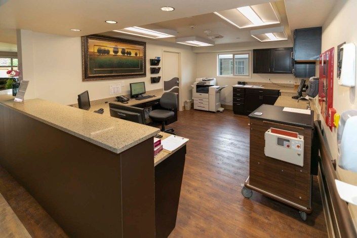 A modern office reception area with desks, computers, and a printer.