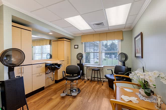 An interior view of a hair salon featuring styling chairs, mirrors, and hair dryers.