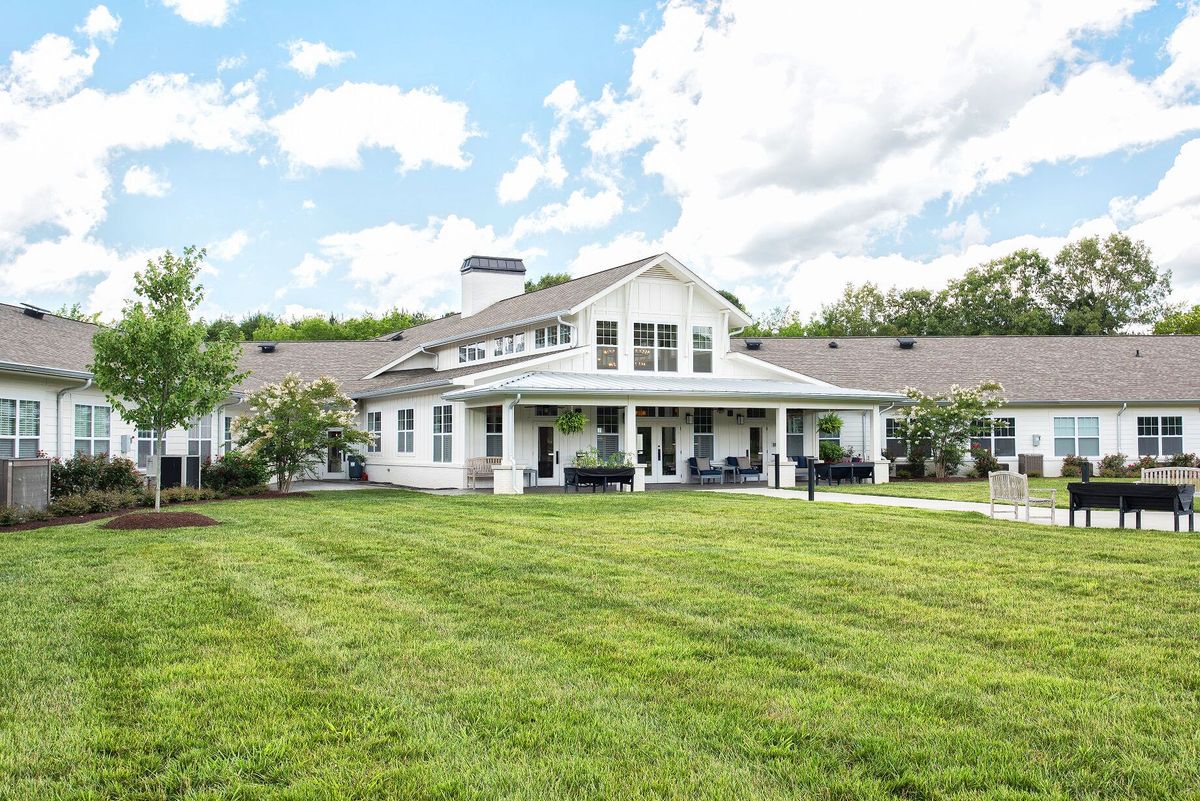 A beautiful countryside home with a well-maintained lawn and a clear, cloudy sky.