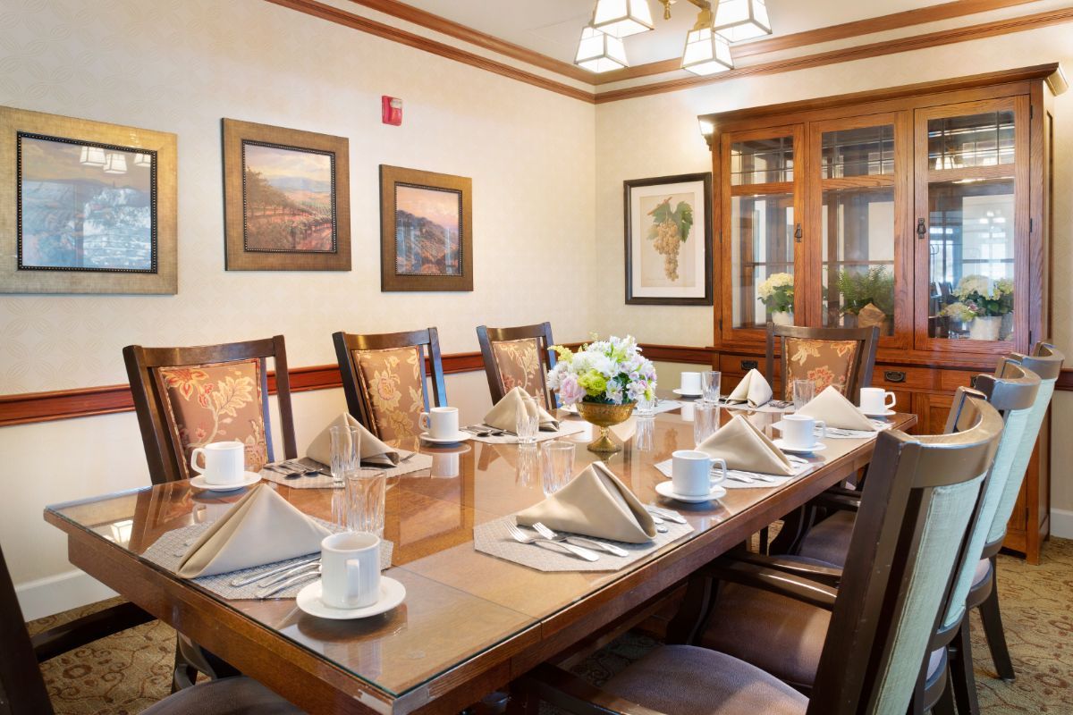 A formal dining room elegantly set with napkins and cups around a polished wooden table.