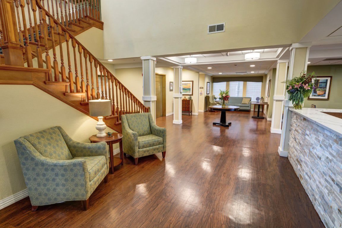 A cozy and open lobby area featuring wooden flooring, comfortable seating, and a staircase.