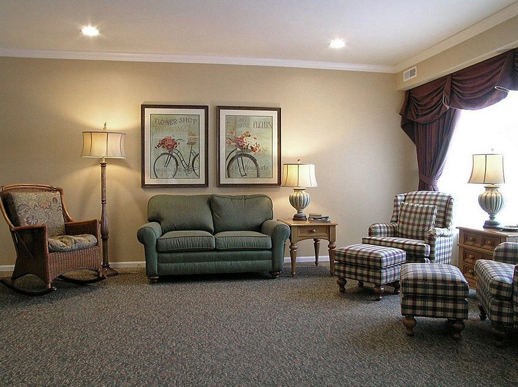 A cozy living room with a sofa, armchairs, and decorative elements such as lamps and wall art.