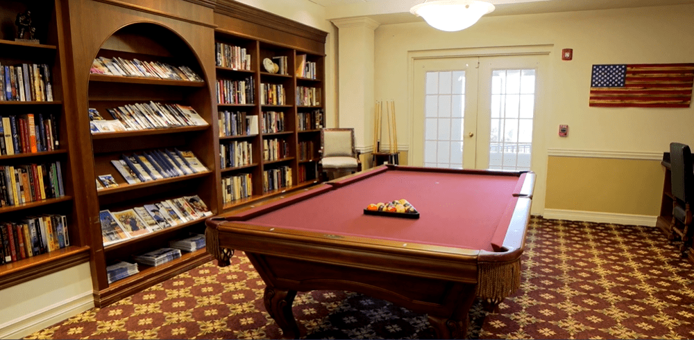 A cozy room featuring a pool table and bookshelves filled with books.