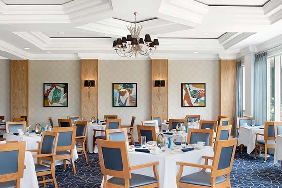Elegant dining room with neatly set tables and colorful wall art.