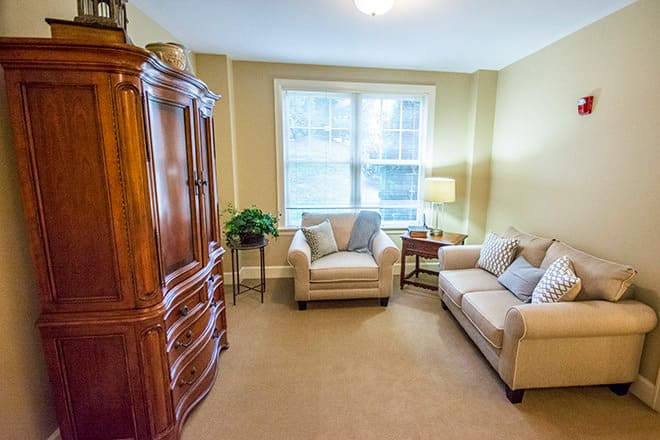 A cozy living room with a window, sofas, and a wooden cabinet.