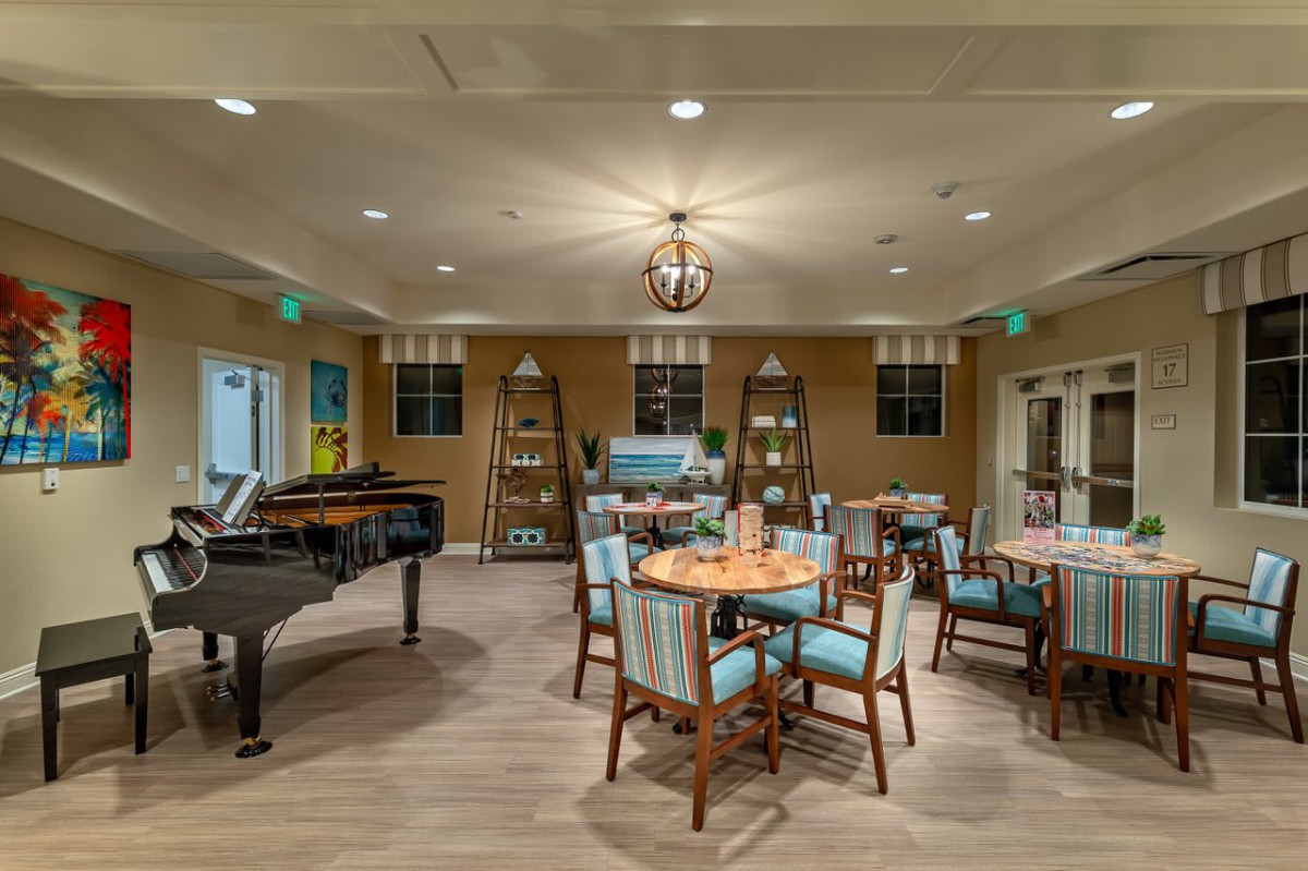 A cozy and elegantly furnished dining area featuring a grand piano, comfortable seating, and warm lighting.