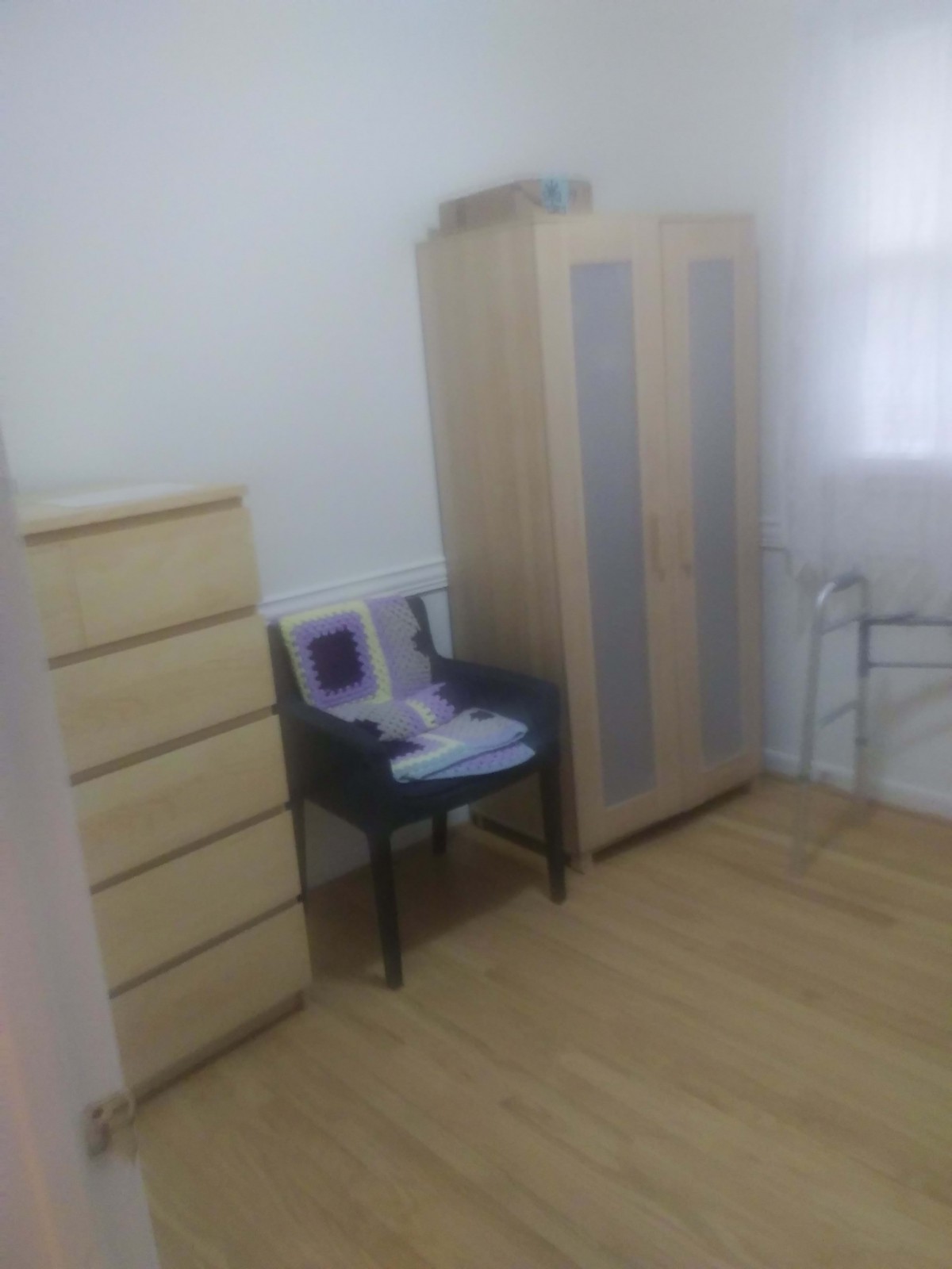 A minimalist bedroom with a wardrobe, dresser, and chair.
