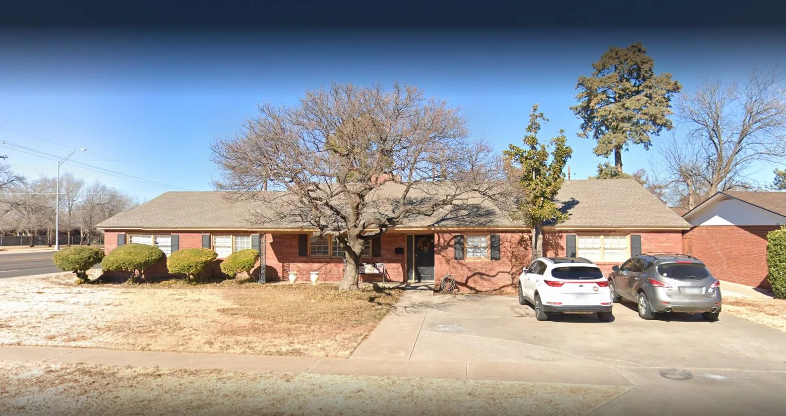 A suburban brick house with a driveway and parked car.