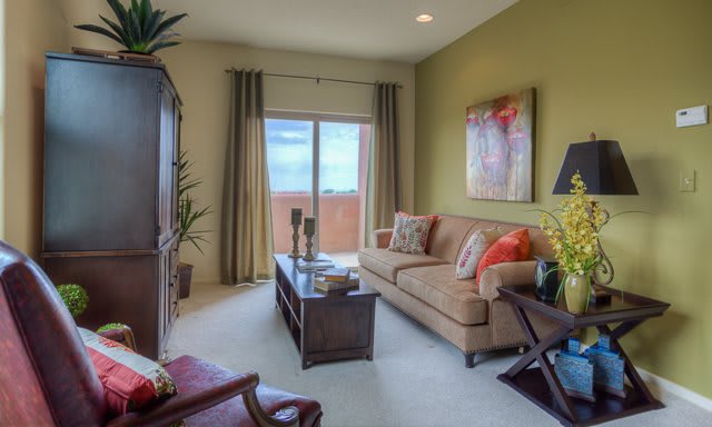 A cozy living room featuring a comfortable sofa, coffee table, and large window with curtains.