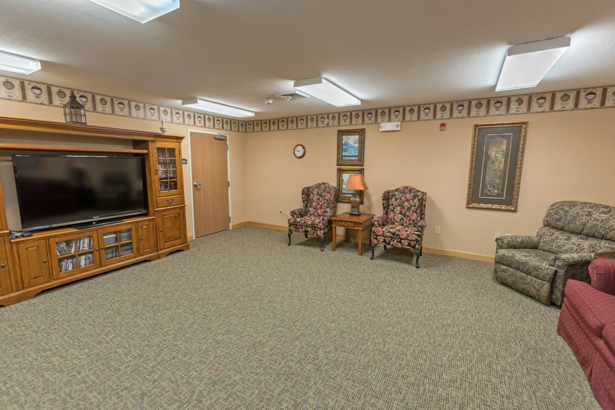 A cozy living room with armchairs, a television, and wall decorations.