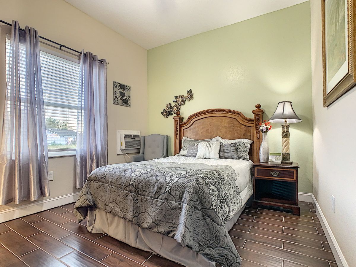 A cozy bedroom with a neatly made bed, a lamp on the nightstand, and soft lighting.
