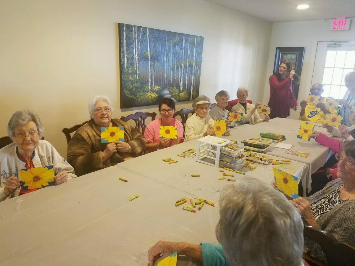 A group of seniors participating in a flower craft activity indoors.