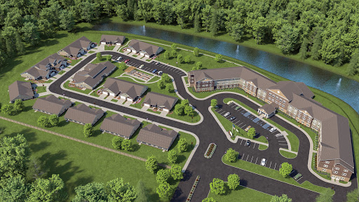 Aerial view of a planned residential community with landscaped grounds and winding roads near a river.