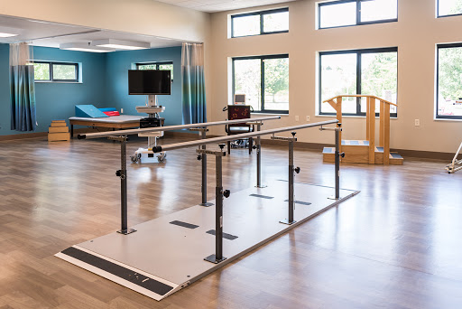 A well-equipped rehabilitation space featuring parallel bars and a wooden exercise aid, designed for physical therapy.