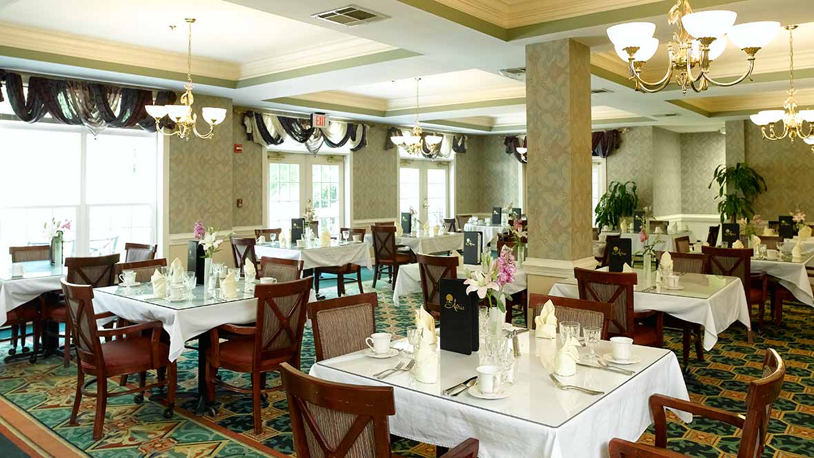 A formal dining room with elegantly set tables and chandeliers.