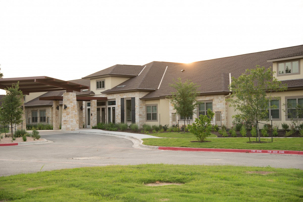 A modern residential building with a spacious driveway and well-maintained landscape.